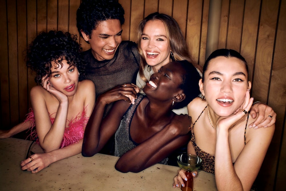 Group of friends with event-ready hair and makeup laughing together at a party